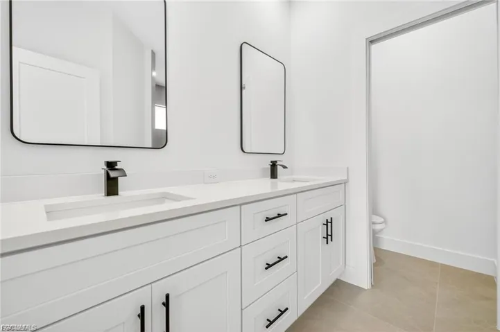 Full bath with double vanity and light tile patterned flooring