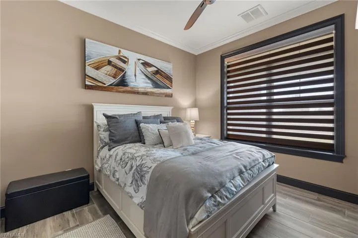 Bedroom #2 with Plank Tile floors, ceiling fan, and crown Molding above.
