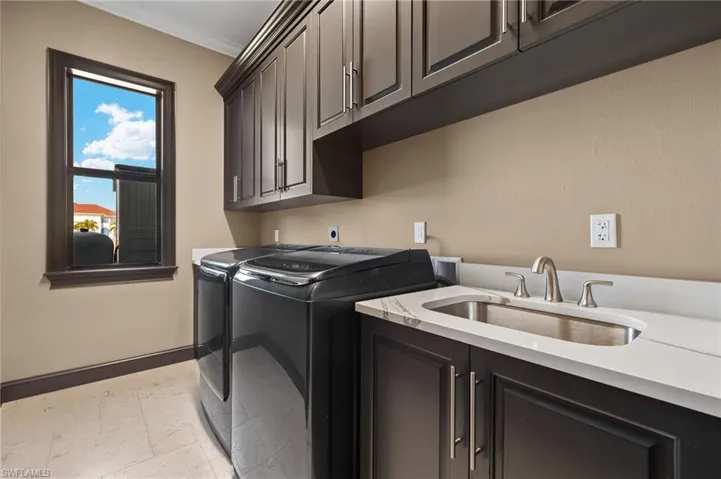 Laundry area with crown molding, washer and dryer, sink, and cabinets for plenty of storage.