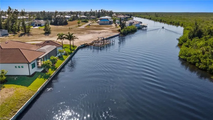 Drone / aerial water view of wide canal navigable by larger and smaller watercraft.  No bridges to ocean water.