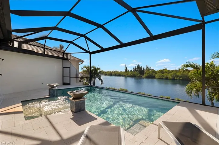 View of swimming pool featuring a fully screened enclosure, a beautiful water view looking down the extra wide spreader canal.