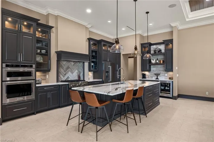 Kitchen with a center island with sink, hanging light fixtures, wine cooler, and tasteful backsplash