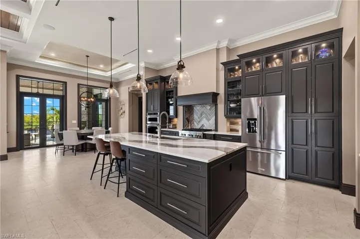 Kitchen with tasteful backsplash, elegant quartz countertops, high quality fridge, pendant lighting, and an extra large  island