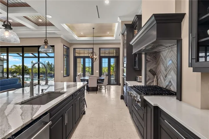 Kitchen with french doors, ornamental molding, stainless steel appliances, sink, decorative light fixtures. and Jenn-Aire gas cooktop.
