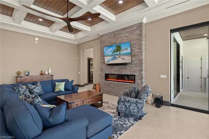Living room featuring coffered ceiling, beamed ceiling, a fireplace, wood ceiling, and ornamental molding