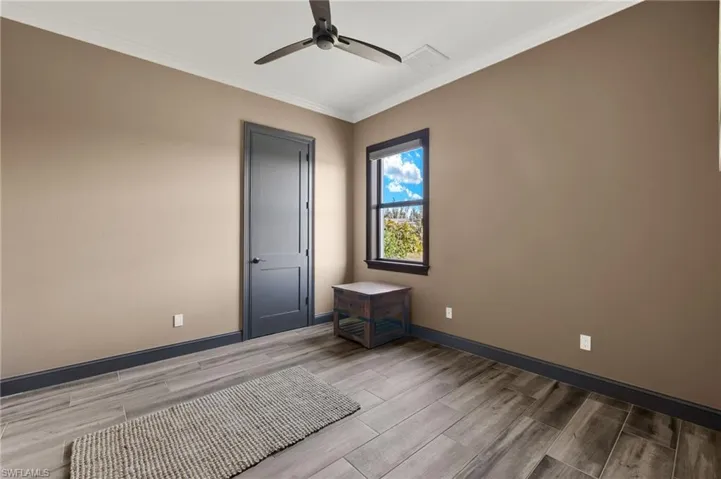 Bedroom #3 with a wood plank flooring, crown molding, and a spacious closet.