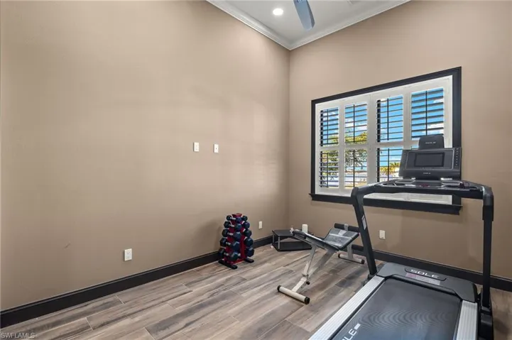 Workout area/or 4th bedroom with wood planked tile flooring and crown molding