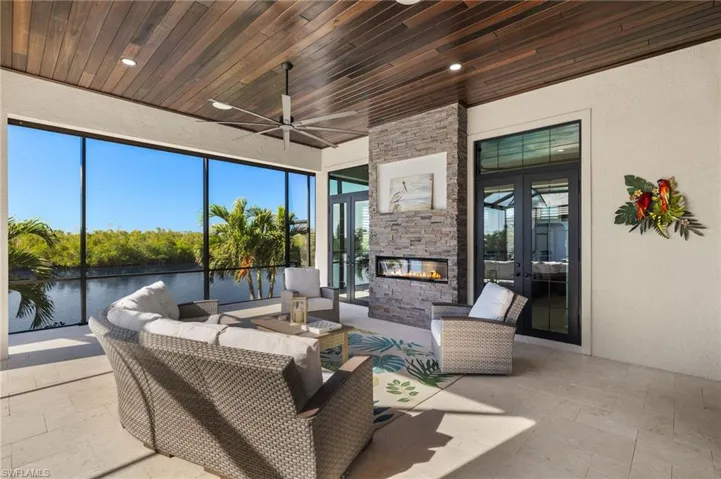 Sunroom / solarium with french doors, an outdoor stone fireplace, ceiling fan, a water view, and wooden ceiling.  Great area for entertaining guests or just a relaxing evening by the outdoor fireplace.