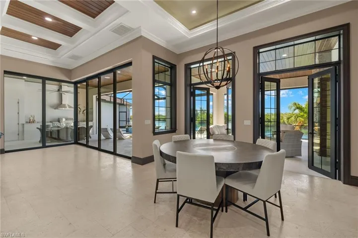 Dining room with crown molding, beamed ceiling, coffered ceiling, and french doors that open to the lanai/sunroom area.