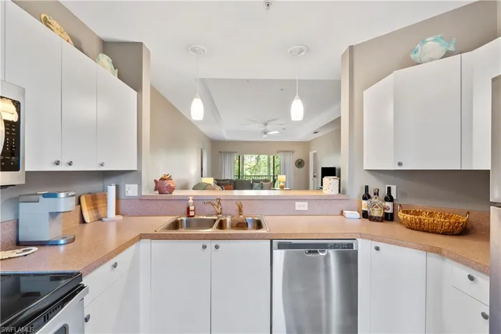 Kitchen with pendant lighting, white cabinets, sink, and stainless steel dishwasher