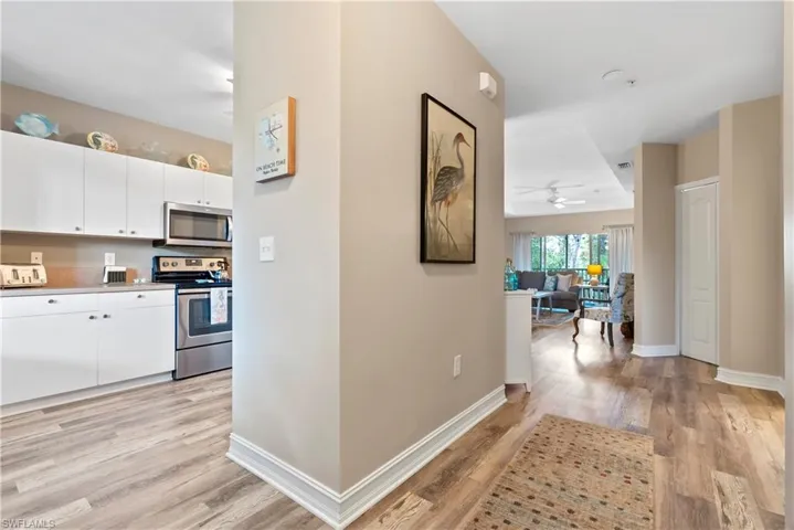 Kitchen with ceiling fan, stainless steel appliances, light hardwood / wood-style floors, and white cabinetry