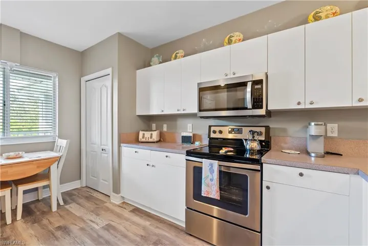 Kitchen with appliances with stainless steel finishes, light hardwood / wood-style flooring, and white cabinets
