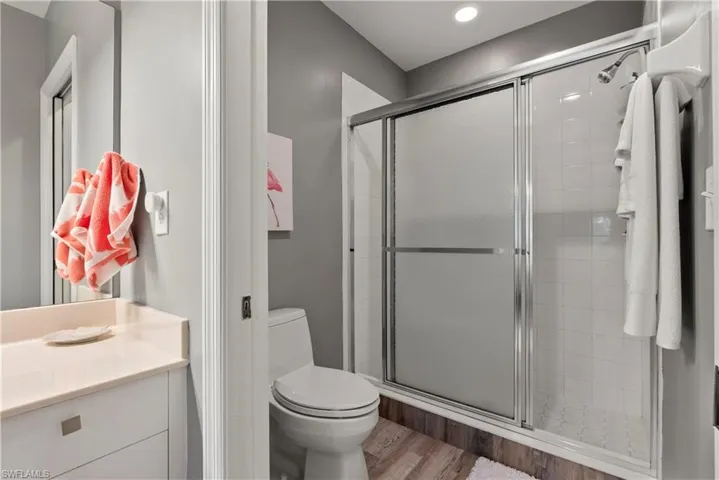 Bathroom with walk in shower, hardwood / wood-style floors, vanity, and toilet