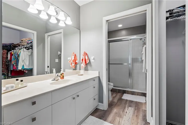 Bathroom featuring a shower with door, hardwood / wood-style floors, vanity, and toilet