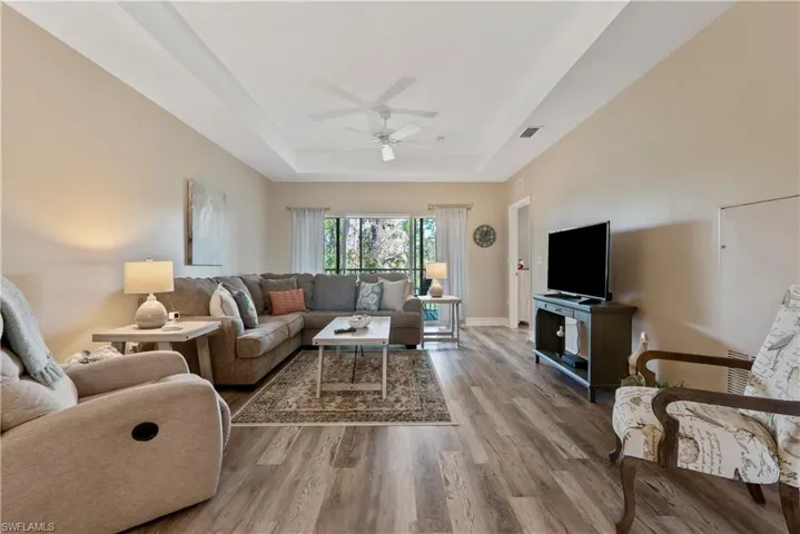 Spacious Living room featuring ceiling fan, light hardwood / wood-style flooring, and a raised ceiling