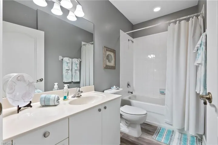 Guest Full bathroom featuring hardwood / wood-style floors, toilet, shower / tub combo, and vanity