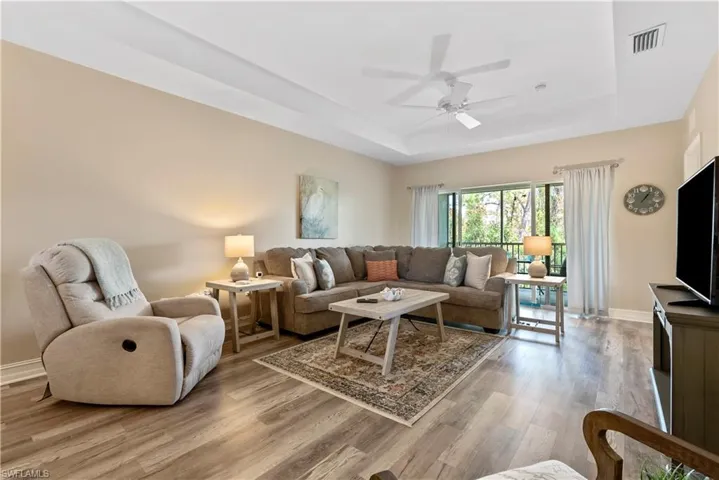 Living room with ceiling fan, light hardwood / wood-style floors, and a raised ceiling