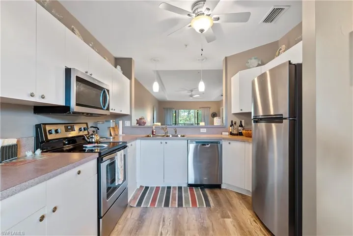 Kitchen with pendant lighting, white cabinets, and appliances with stainless steel finishes