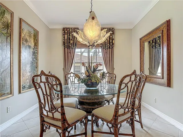 Dining space with crown molding, baseboards, light tile patterned floors, and a chandelier