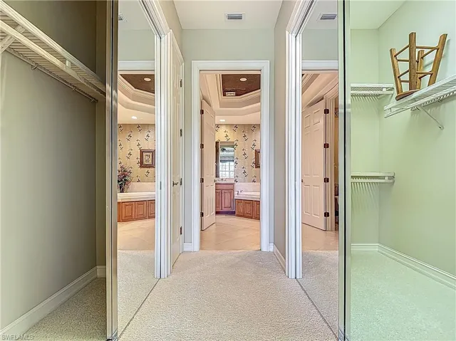 Corridor with light carpet, a raised ceiling, ornamental molding, baseboards, and wallpapered walls