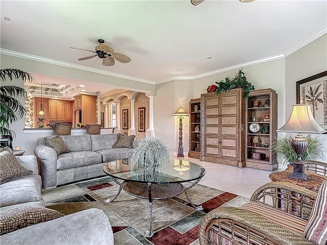 Living room featuring crown molding, decorative columns, ceiling fan, and light tile patterned floors