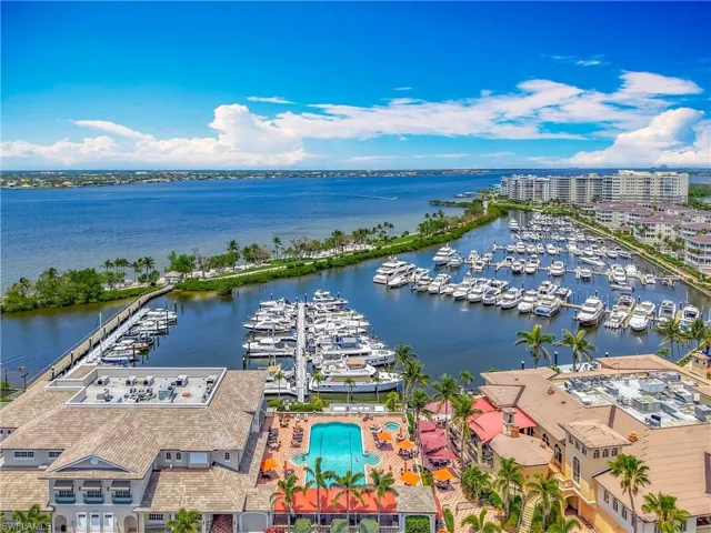 Bird's eye view of a marina, a large body of water, and a pool