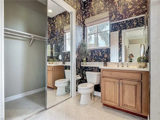 Full bathroom featuring wallpapered walls, toilet, vanity, and baseboards
