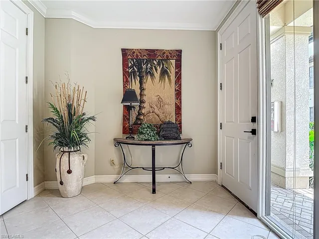 Entryway featuring light tile patterned flooring, ornamental molding, and baseboards