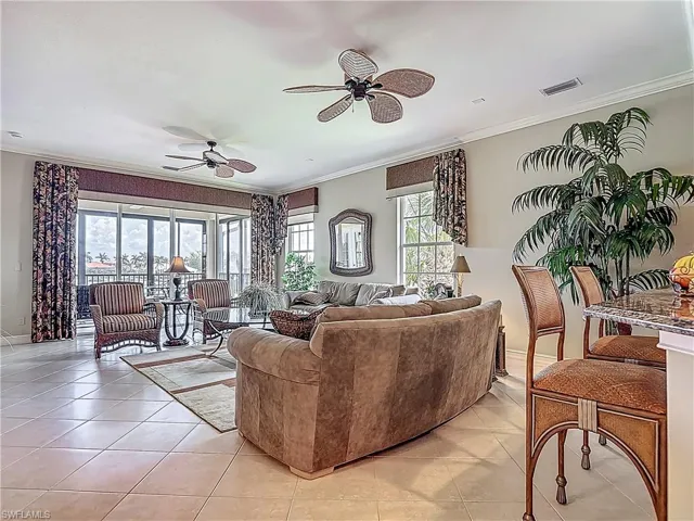 Living area with a ceiling fan, crown molding, light tile patterned flooring, and baseboards