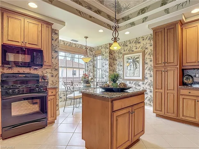 Kitchen featuring black appliances, wallpapered walls, dark stone countertops, brown cabinets, and light tile patterned flooring
