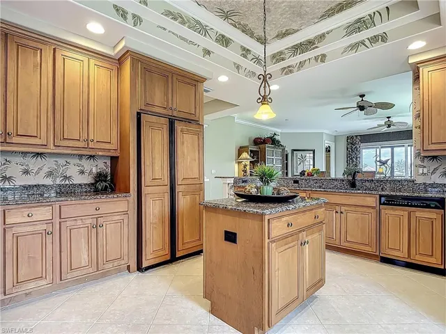 Kitchen featuring paneled appliances, crown molding, a kitchen island, dark stone counters, and ceiling fan