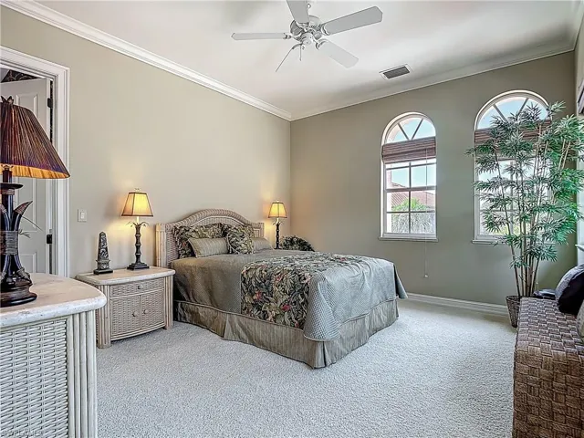 Carpeted bedroom with crown molding, baseboards, and a ceiling fan