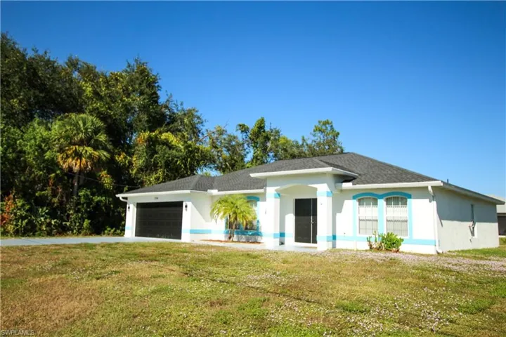 Single story home with a front yard, stucco siding, an attached garage, and driveway