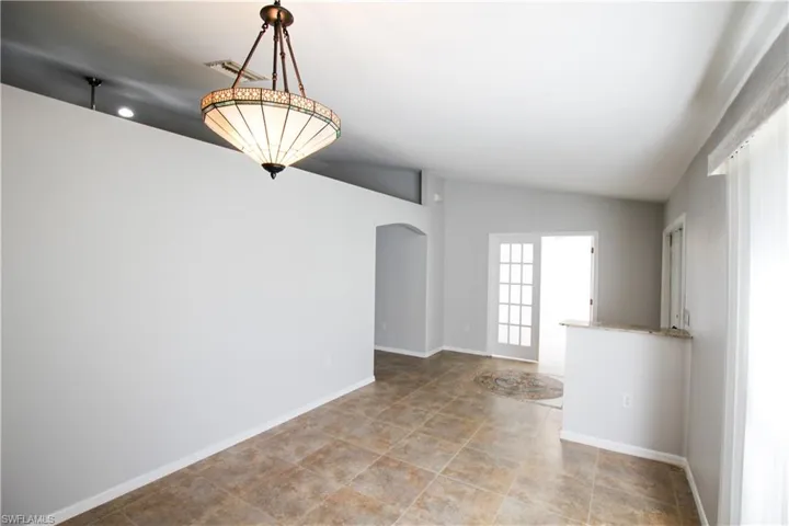 Spare room featuring arched walkways and vaulted ceiling