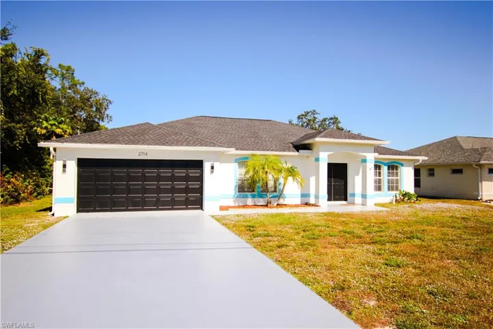 View of front of home with driveway, stucco siding, a front yard, and an attached garage