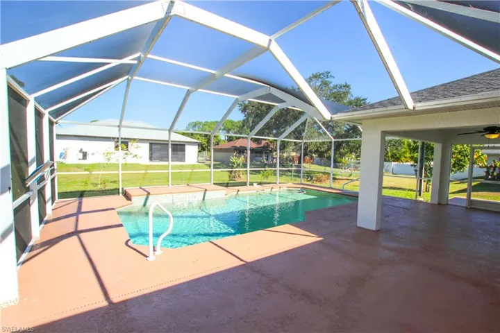 Outdoor pool with a yard, a patio area, a sunroom, and a ceiling fan