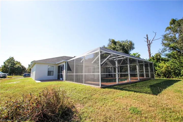 Back of property with a lanai, a yard, a sunroom, and an outdoor pool