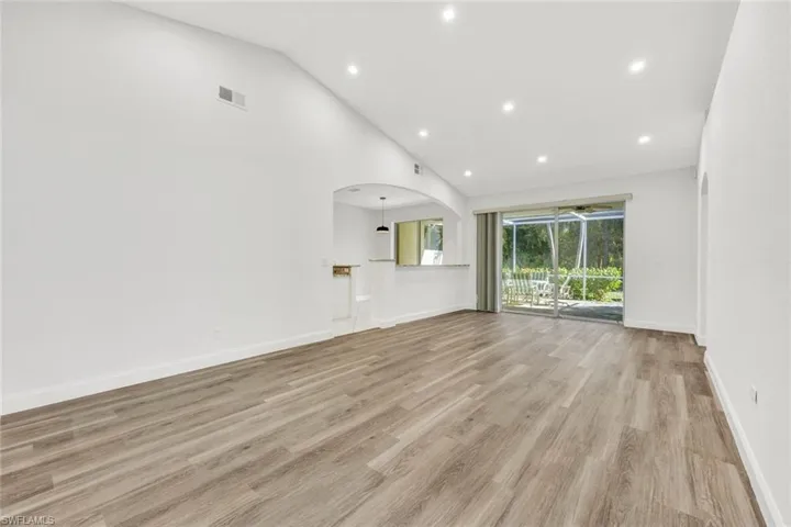 Living room with laminate wood floors, vaulted ceiling, and recessed lighting