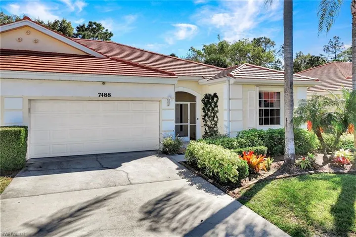 Up close view of Villa with a tile roof, concrete driveway, a garage, and stucco siding.
