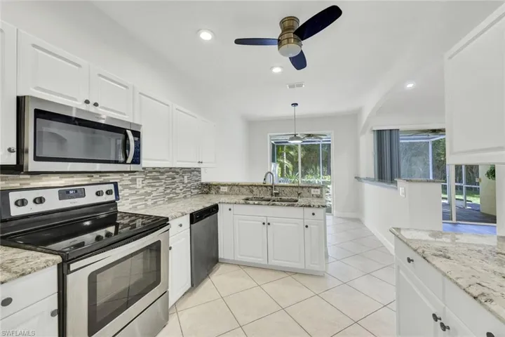 Kitchen featuring stainless steel appliances, white cabinetry, a peninsula, and ceiling fan