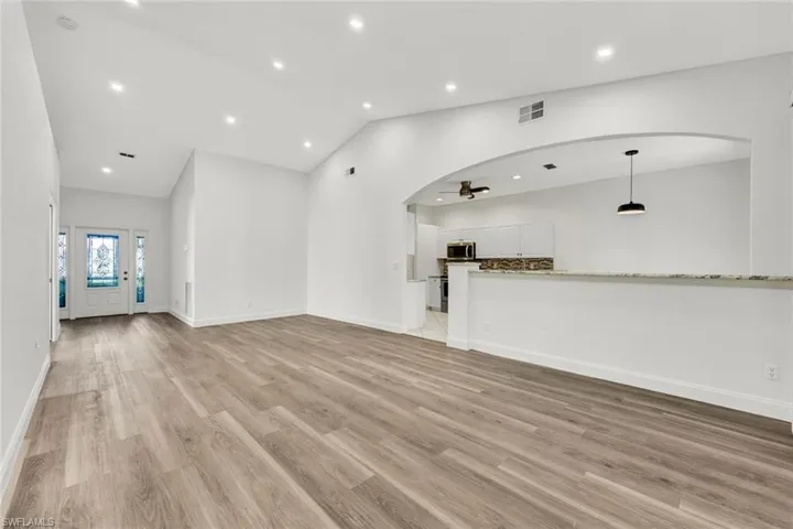 Living room with Vaulted ceiling, light laminate wood floors, recessed lighting