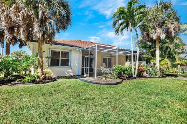 Back of house featuring a fully screened in lanai and patio, stucco siding and yard