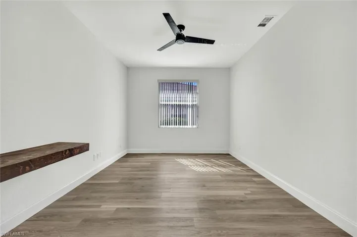 Den/Office room featuring a built in desk, light laminate wood flooring and a ceiling fan