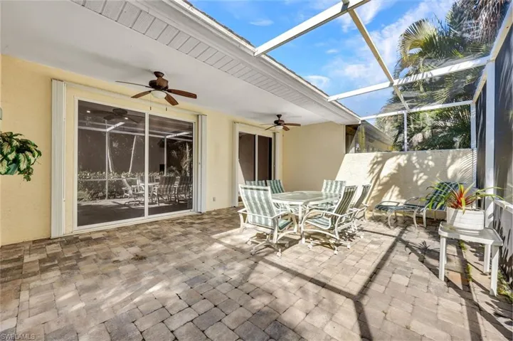 View of screened Lanai patio / terrace featuring an outdoor dining space and two ceiling fans