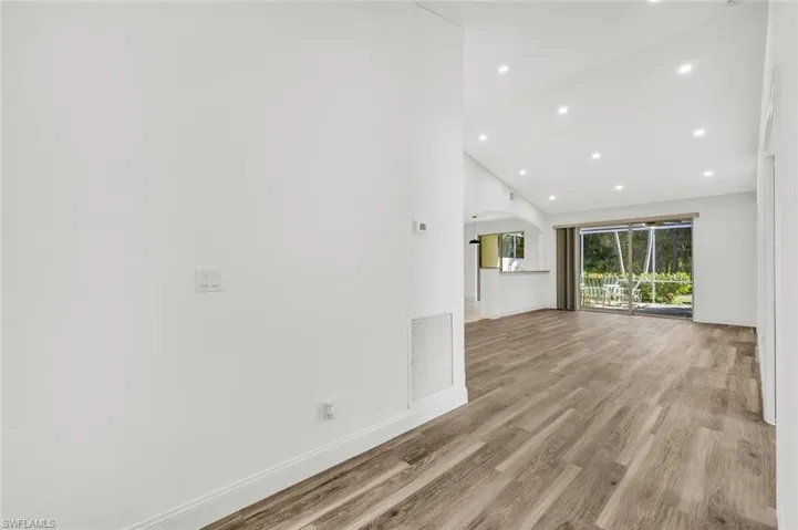 Living room featuring high ceiling, laminate wood floors, and recessed lighting