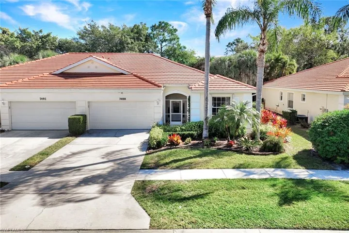 View of villa with driveway, a front lawn, a tile roof, and an attached 2-car garage