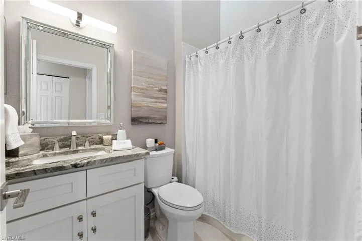 Bathroom with white shaker vanity and granite countertops