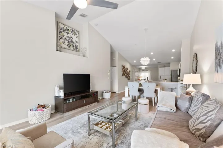 Living room with vaulted ceiling, LVT flooring, and a ceiling fan