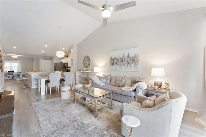 Living room with vaulted ceiling, LVT flooring, and a ceiling fan