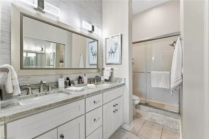 Bathroom with a shower stall, double vanity, and tile patterned flooring